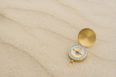 High angle view of navigational compass on sand at beach