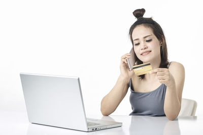 Young woman using mobile phone against white background