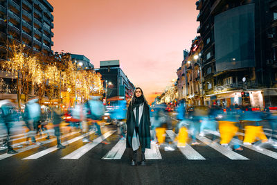 People walking on illuminated city street at dusk