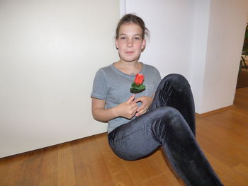 Portrait of smiling girl sitting on hardwood floor at home