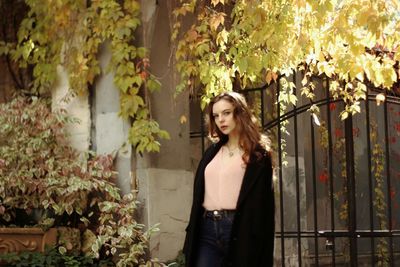 Portrait of young woman standing against gate