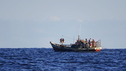 People in boat on sea against clear sky