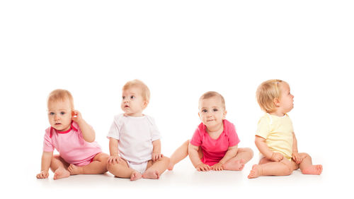 Portrait of siblings sitting on sofa against white background