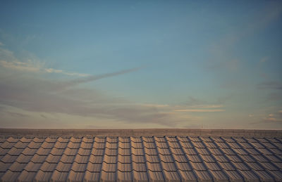 Tilt image of roof tiles against sky