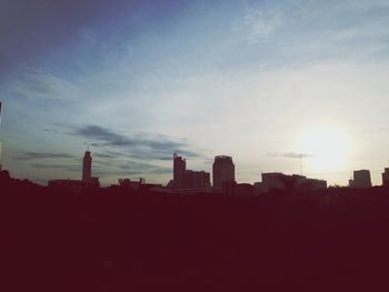 Silhouette buildings in city against sky during sunset