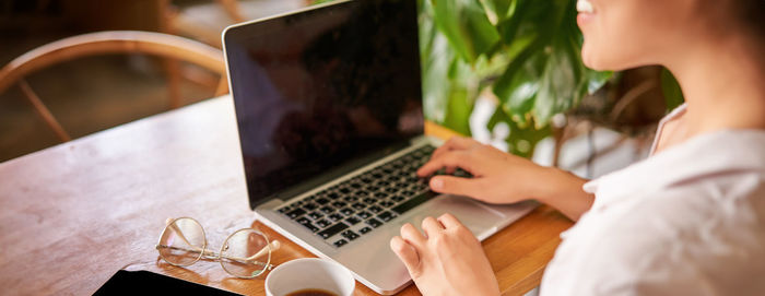 Midsection of woman using laptop on table