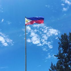 Low angle view of american flag against blue sky