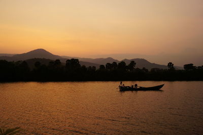 Silhouette boat in lake against sky during sunset