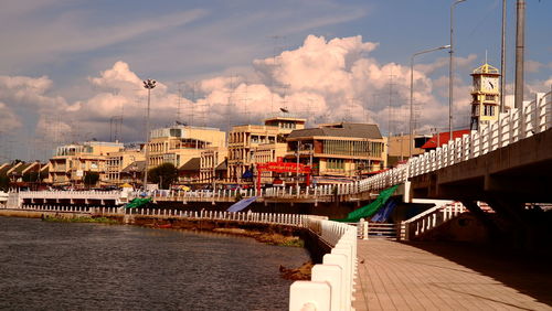 Bridge over river by buildings in city against sky