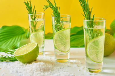 Drink with lime and rosemary on yellow background