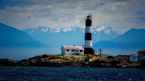 Lighthouse by sea against sky