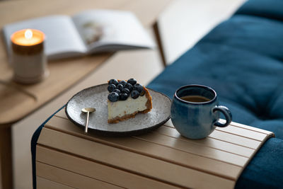 A piece of blueberry cheesecake and a cup of coffee on the couch. cozy room with a reading nook