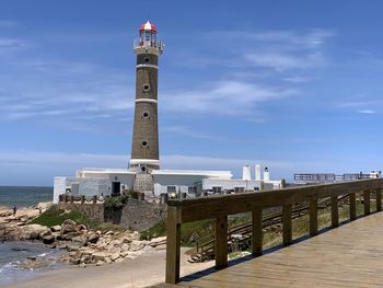 Lighthouse by sea against sky