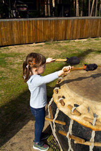 Cute baby playing ethnic drum in the park. the child beats the drum with beaters