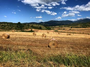 Hay bales on field against sky