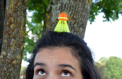 Cropped image of young woman with shuttlecock on head