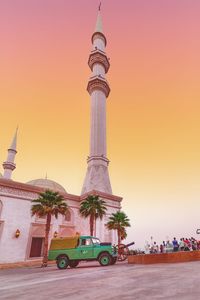 Communications tower in city against sky during sunset