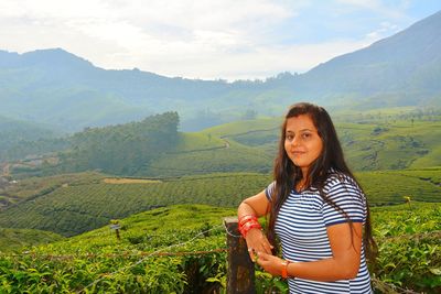 Portrait of smiling young woman standing tea plantation