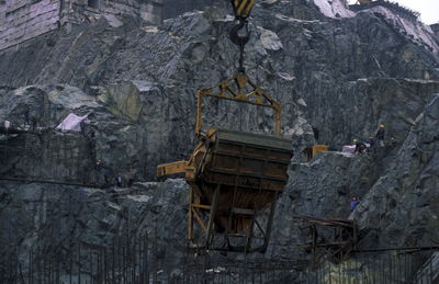 Low angle view of crane against rocky mountains at construction site