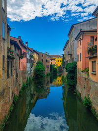 Canal amidst buildings in town against sky