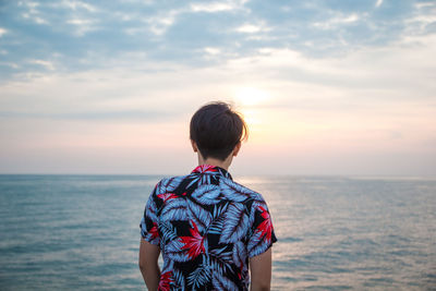 Rear view of man looking at sea against sky