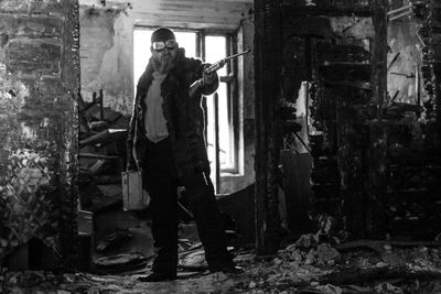 Full length of man standing with gun in abandoned room