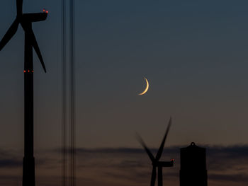 Silhouette windmills against sky at night