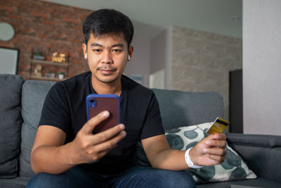 Young man using mobile phone while sitting on sofa