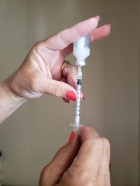 Close-up of woman hands filling medicine from bottle in syringe