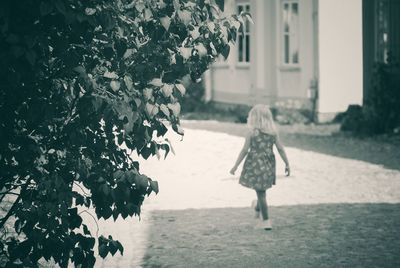 Rear view of girl walking on road during sunny day