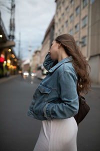 Side view of woman standing on road in city