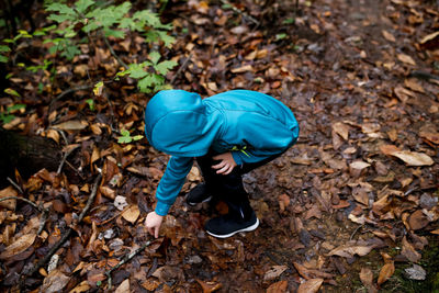 High angle view of man wearing autumn leaves on field