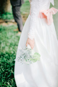 Midsection of woman standing by white flower