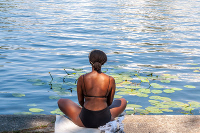 Rear view of woman sitting by lake