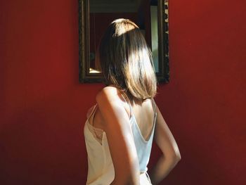 Rear view of woman standing against red wall