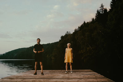 Portrait of woman standing by lake against sky