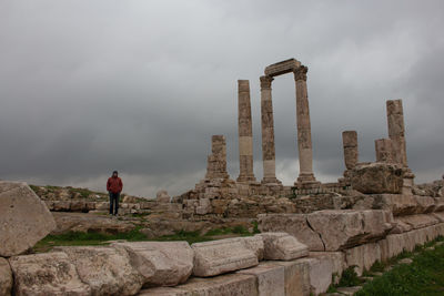 Man standing by temple of hercules against cloudy sky