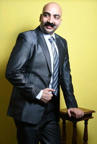 Businessman standing against yellow background