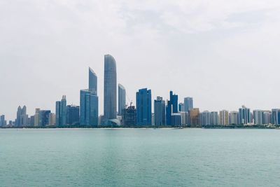 Sea by buildings against sky in city