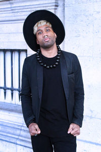 Portrait of young man standing against wall