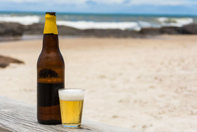 Beer in glass by bottle on table at beach