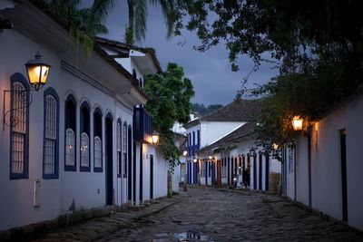 Illuminated street amidst buildings at night