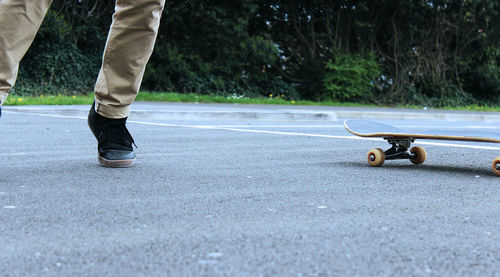 Low section of man by skateboard on road