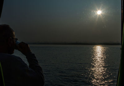 Side view of two people in sea against sky
