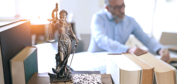 Close-up of lady justice on table with lawyer in background at office