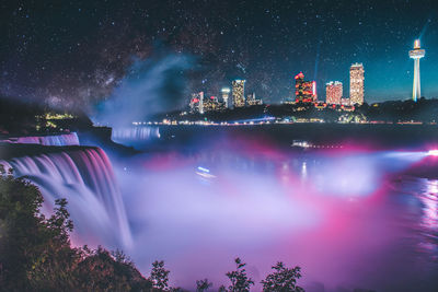 Illuminated buildings against sky at night