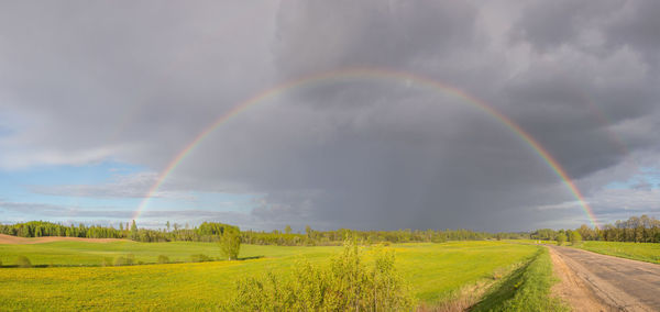 Scenic view of rainbow over field against sky