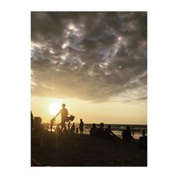 Silhouette people on beach against sky during sunset