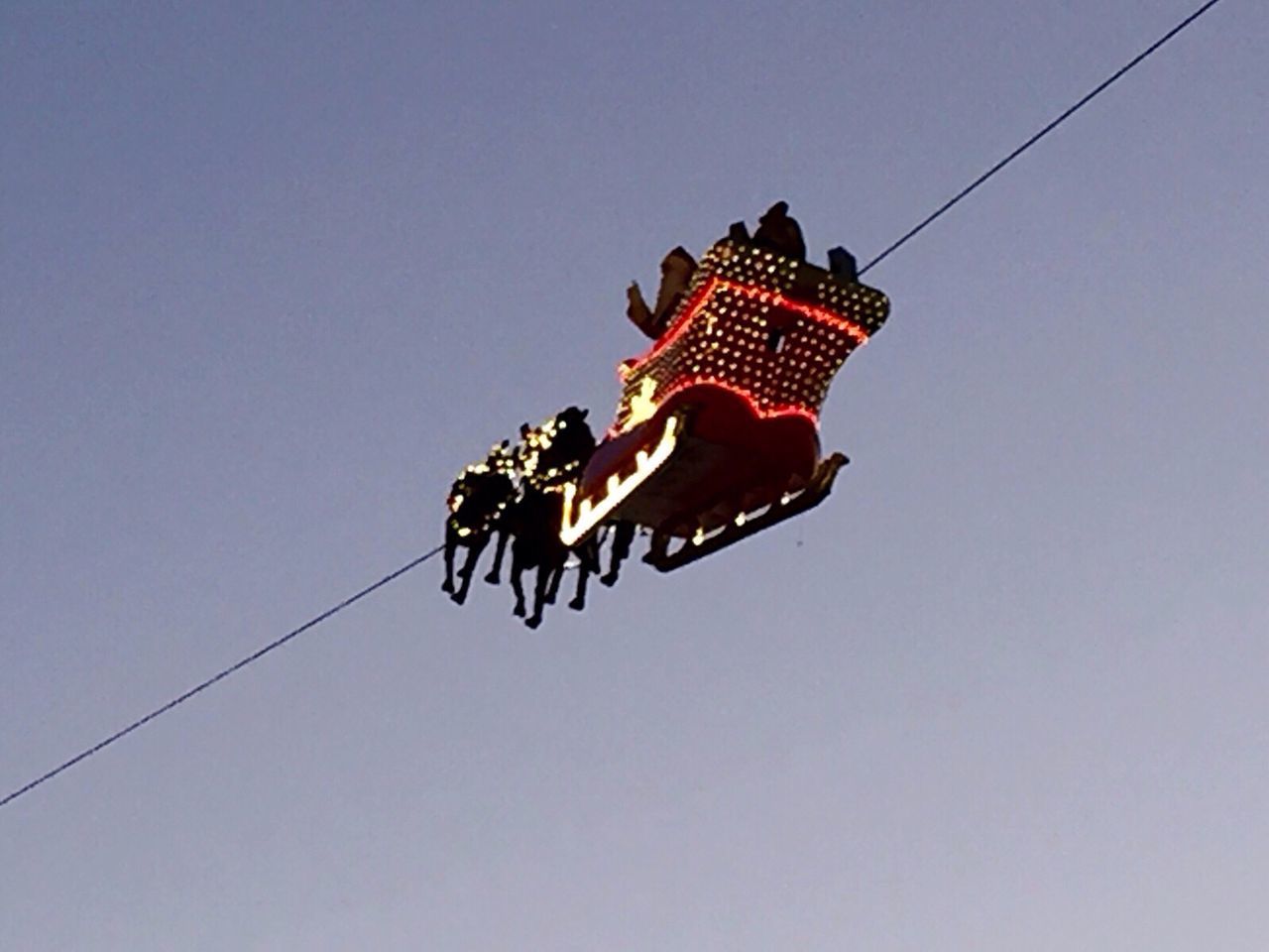 low angle view, clear sky, copy space, blue, arts culture and entertainment, outdoors, hanging, sky, animal representation, no people, day, lighting equipment, red, cable, flying, art, motion, street light, amusement park, lantern