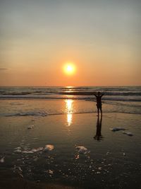 Silhouette man standing on beach against sky during sunset